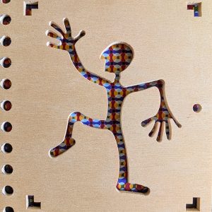 Original-Fotografie von Eva Leopoldi für das Kunstprojekt "Dialog mit der Maschine". Zu sehen ist eine aus einer Holzplatte gestanzte tanzende Figur. Durch die Ausstanzung ist ein farbiger Hintergrund im Pop-Art-Stil zu erkennen.